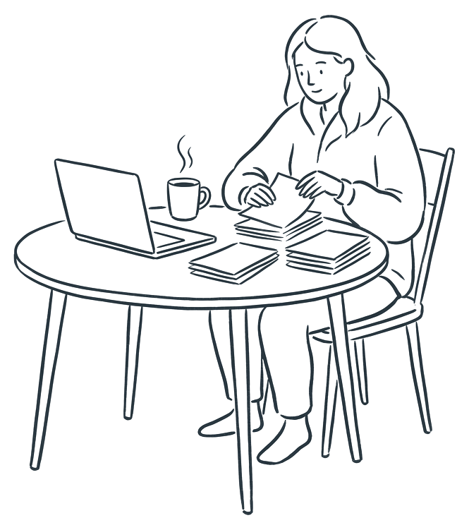 A person at a kitchen table with a mug of tea and a laptop, sorting a small stack of statements.